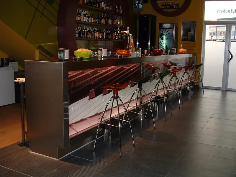 Barra de bar con taburetes y frente iluminado